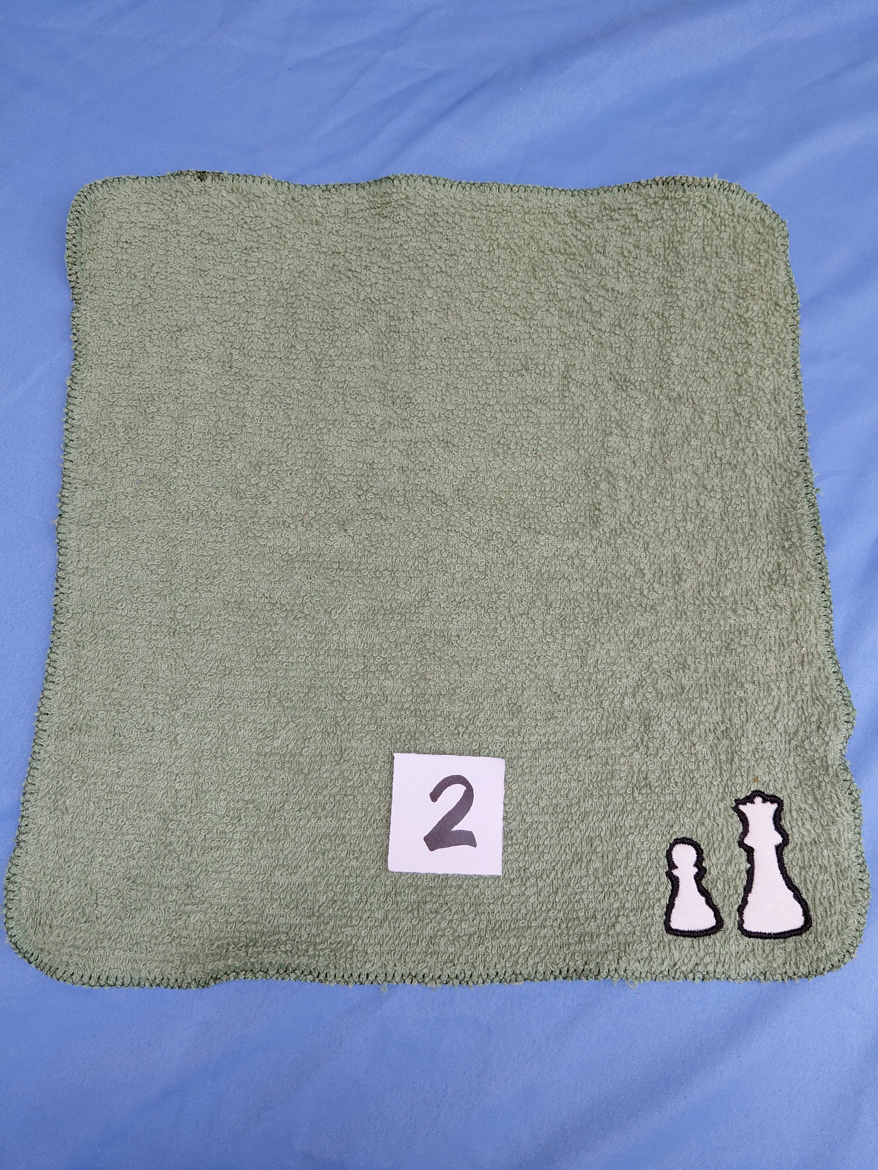 Sage green embellished washcloth with two chess pieces, reinforced hem