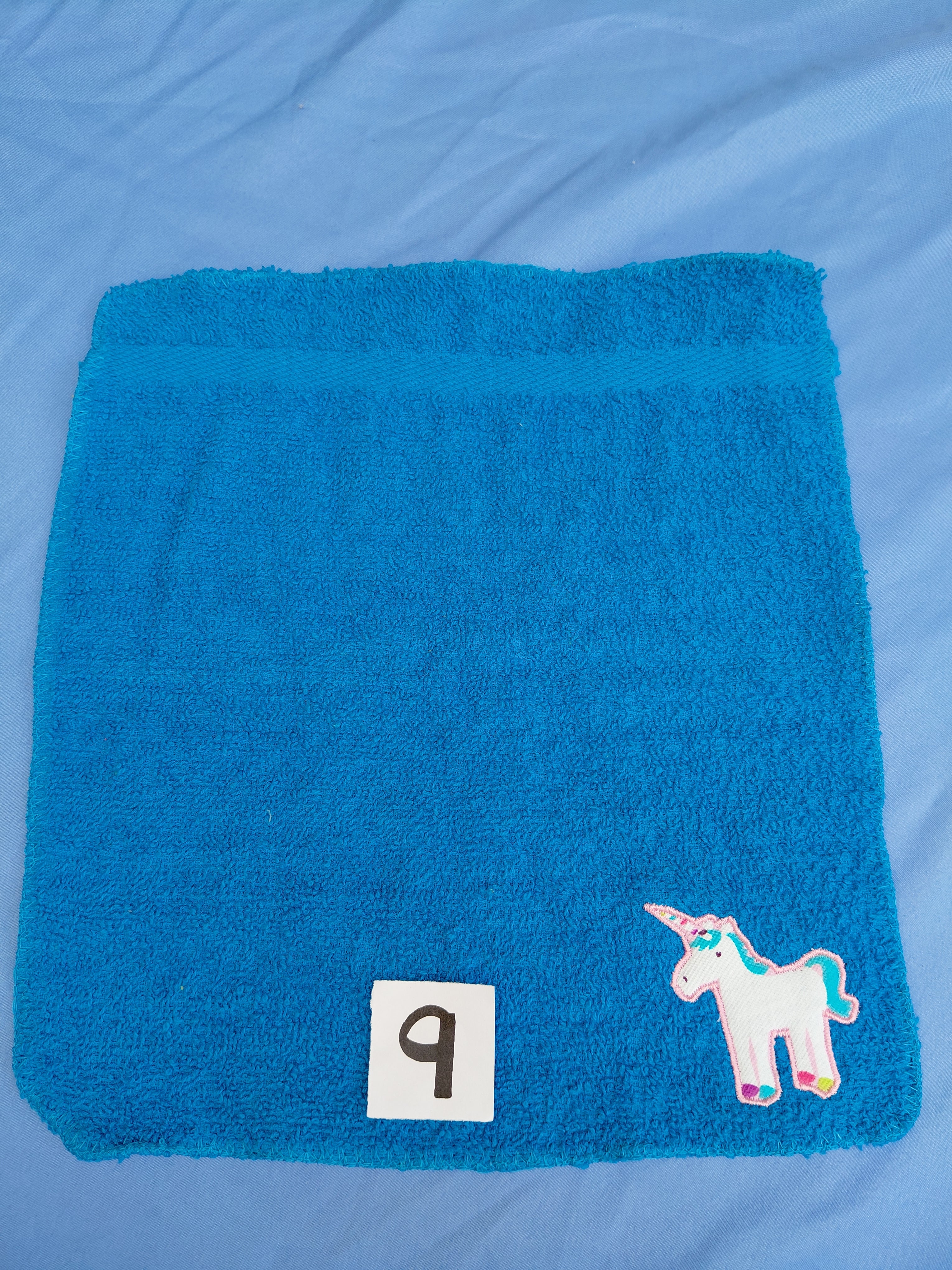 Bright aqua blue embellished washcloth with unicorn, reinforced hem