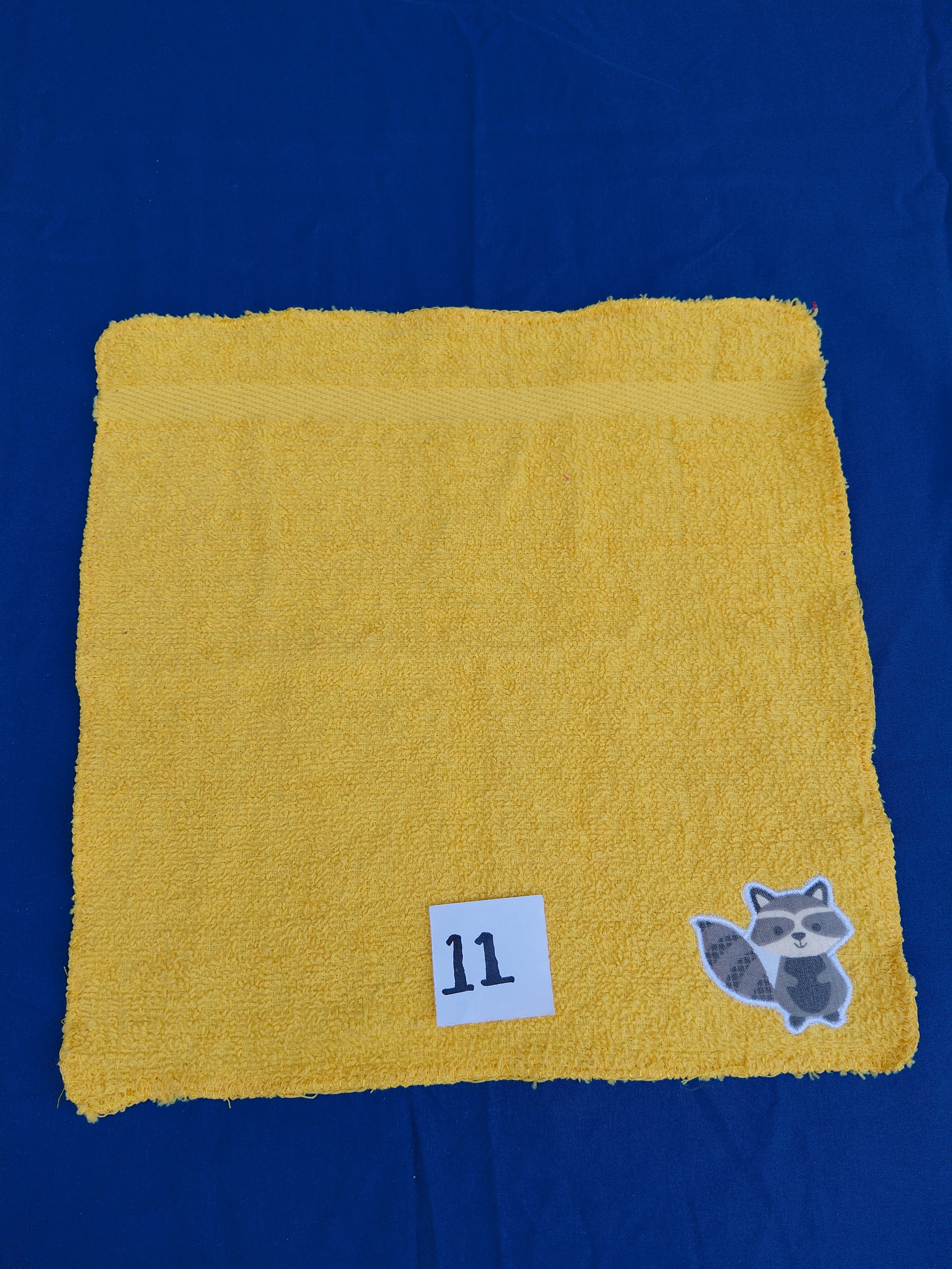 Bright deep gold embellished washcloth with raccoon, reinforced hem

