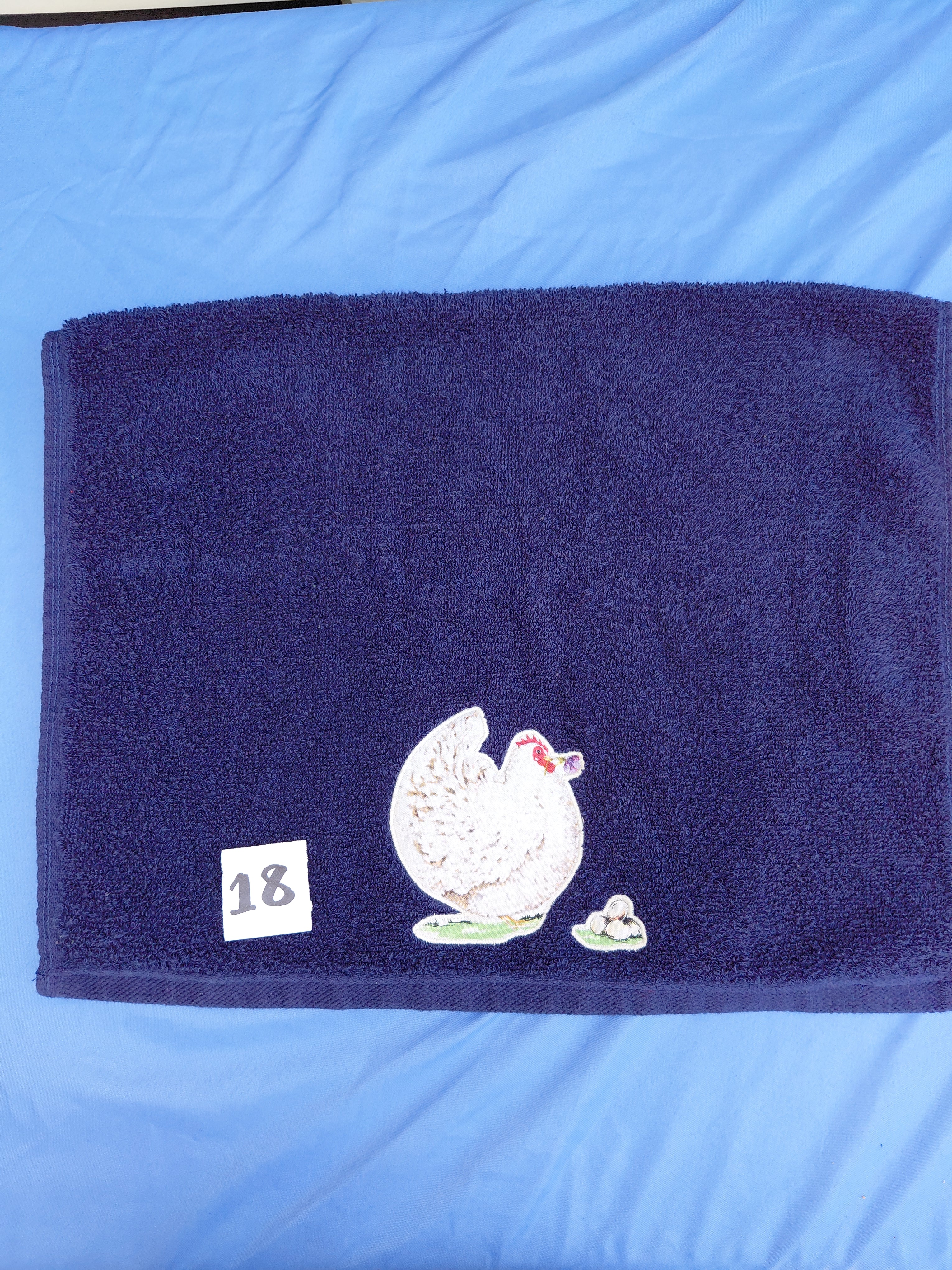 Dark blue embellished hand towel with hen and three eggs, reinforced hem