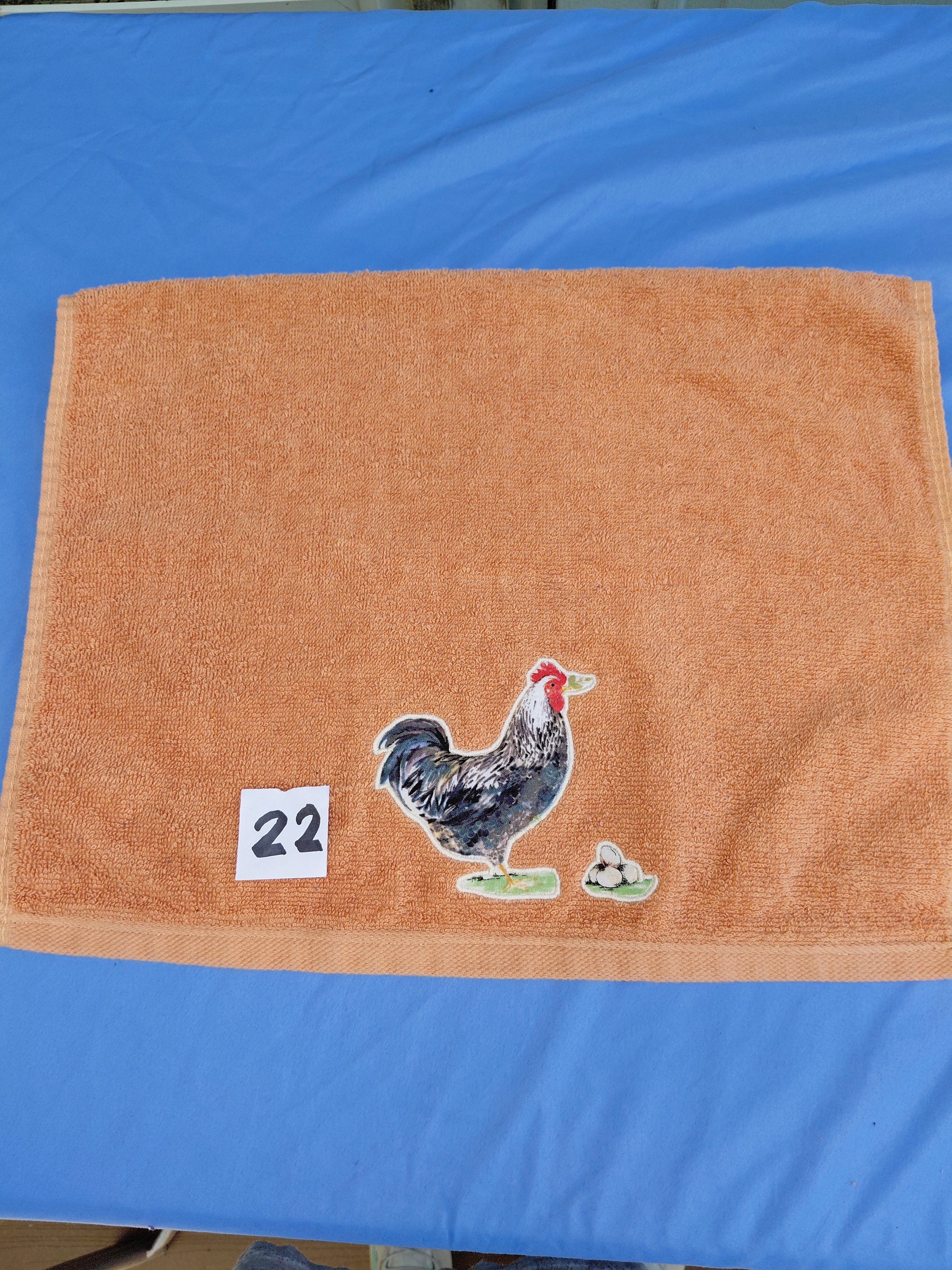 Burnt orange embellished hand towel with rooster and three eggs, reinforced hem