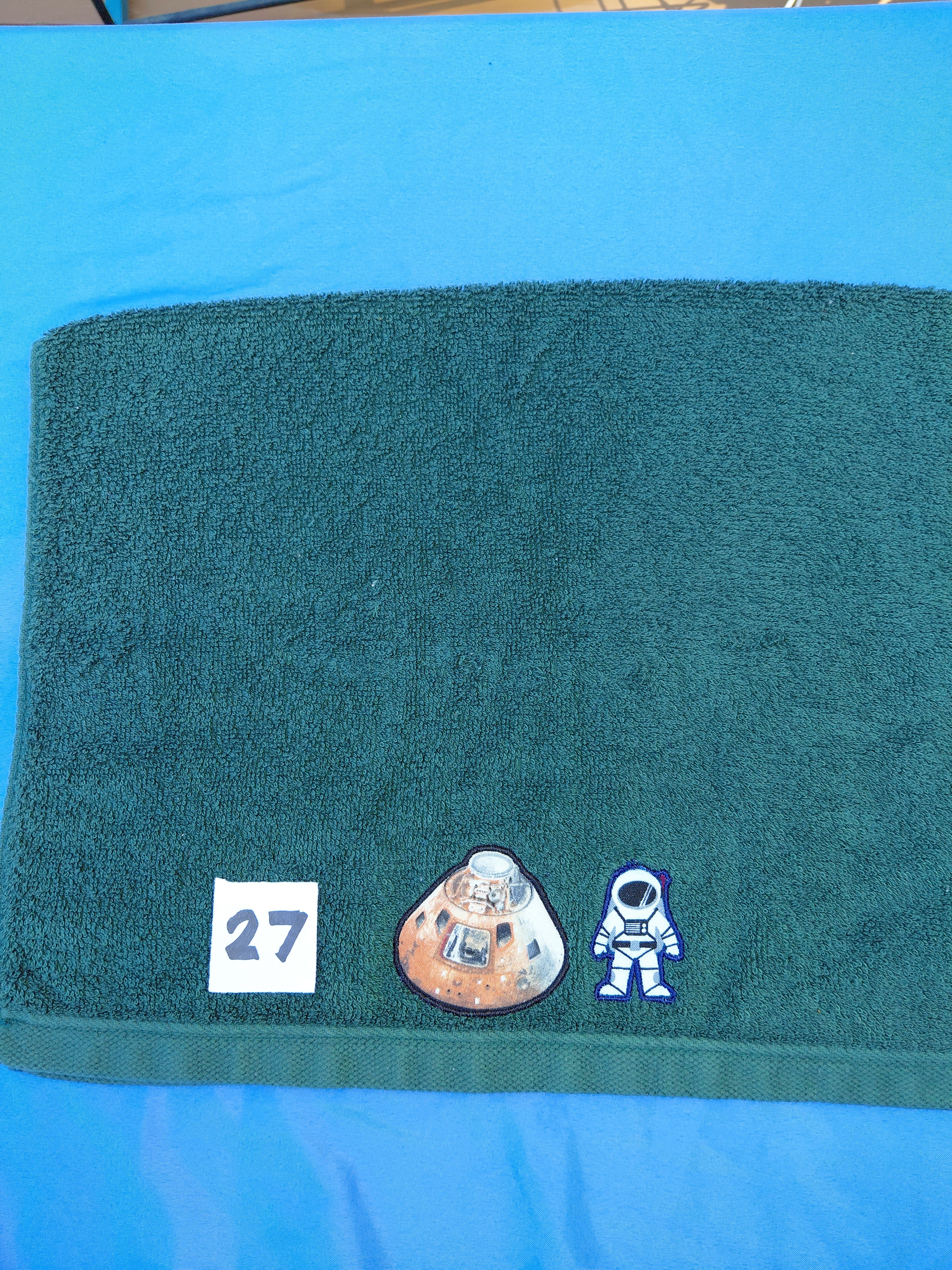 Dark forest green embellished hand towel with astronaut and space capsule, reinforced hem