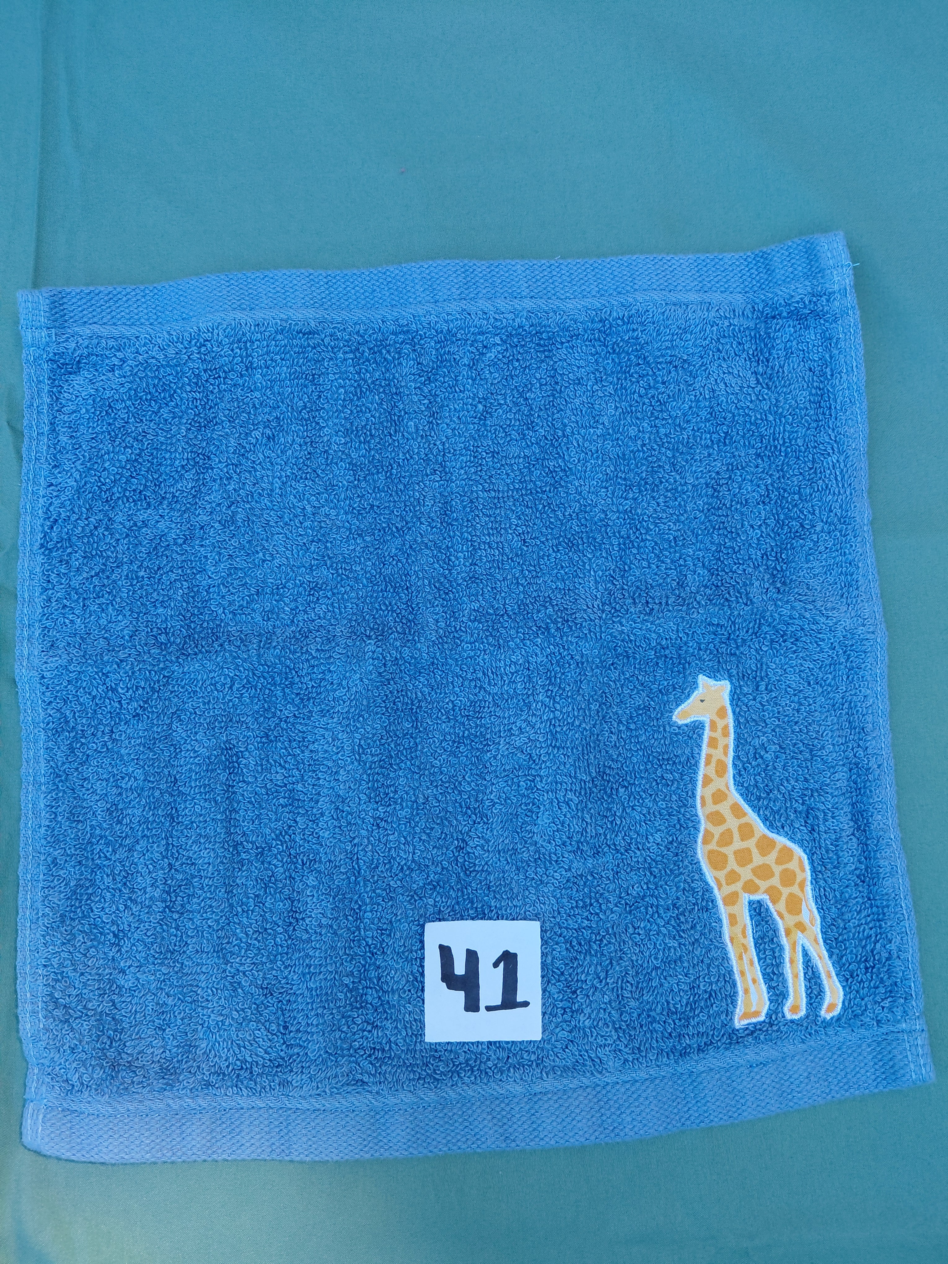 Sky blue handcrafted embellished washcloth with giraffe appliqué, reinforced hem