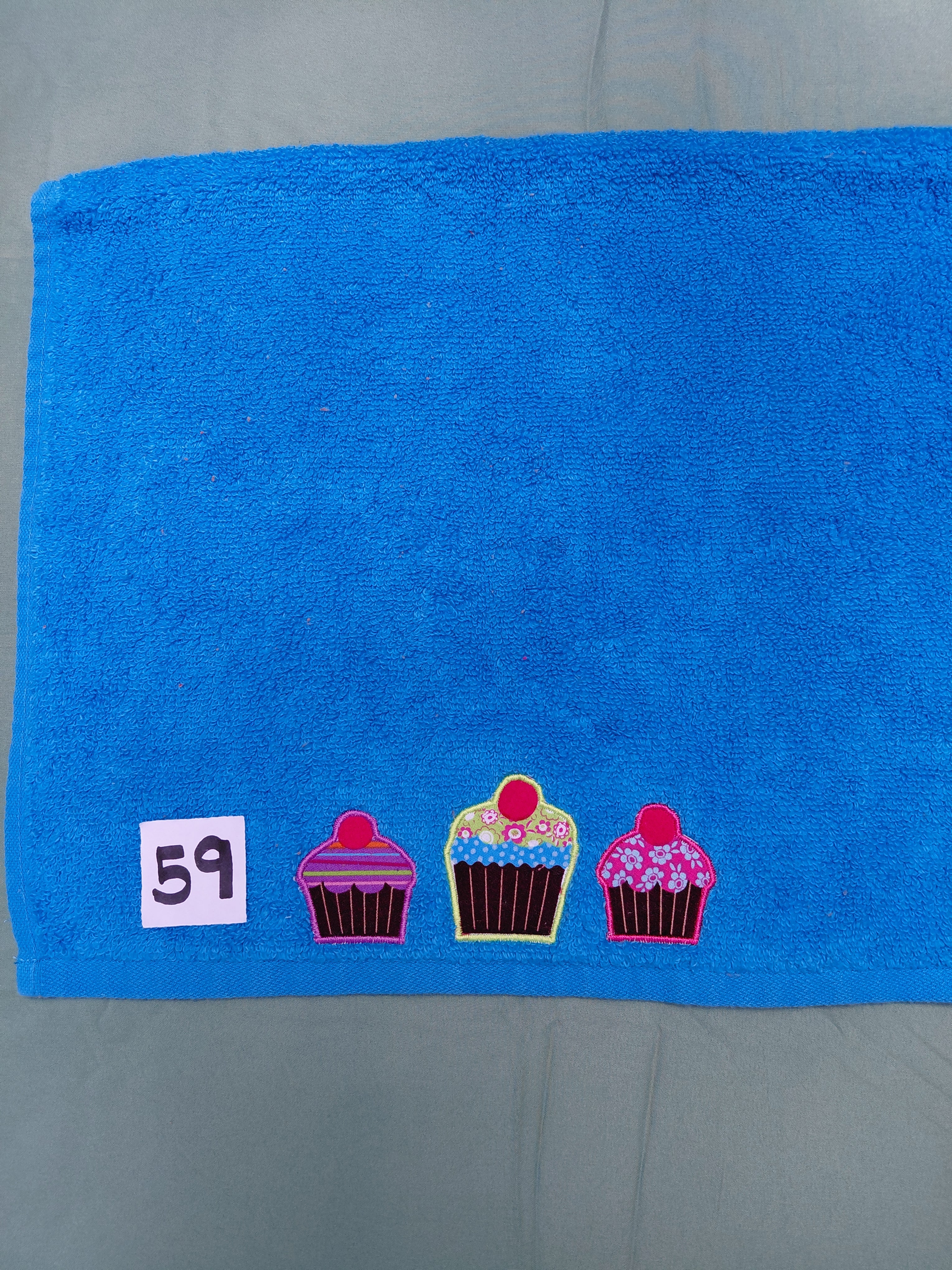 Aqua handcrafted embellished hand towel with three cupcakes appliqué, reinforced hem