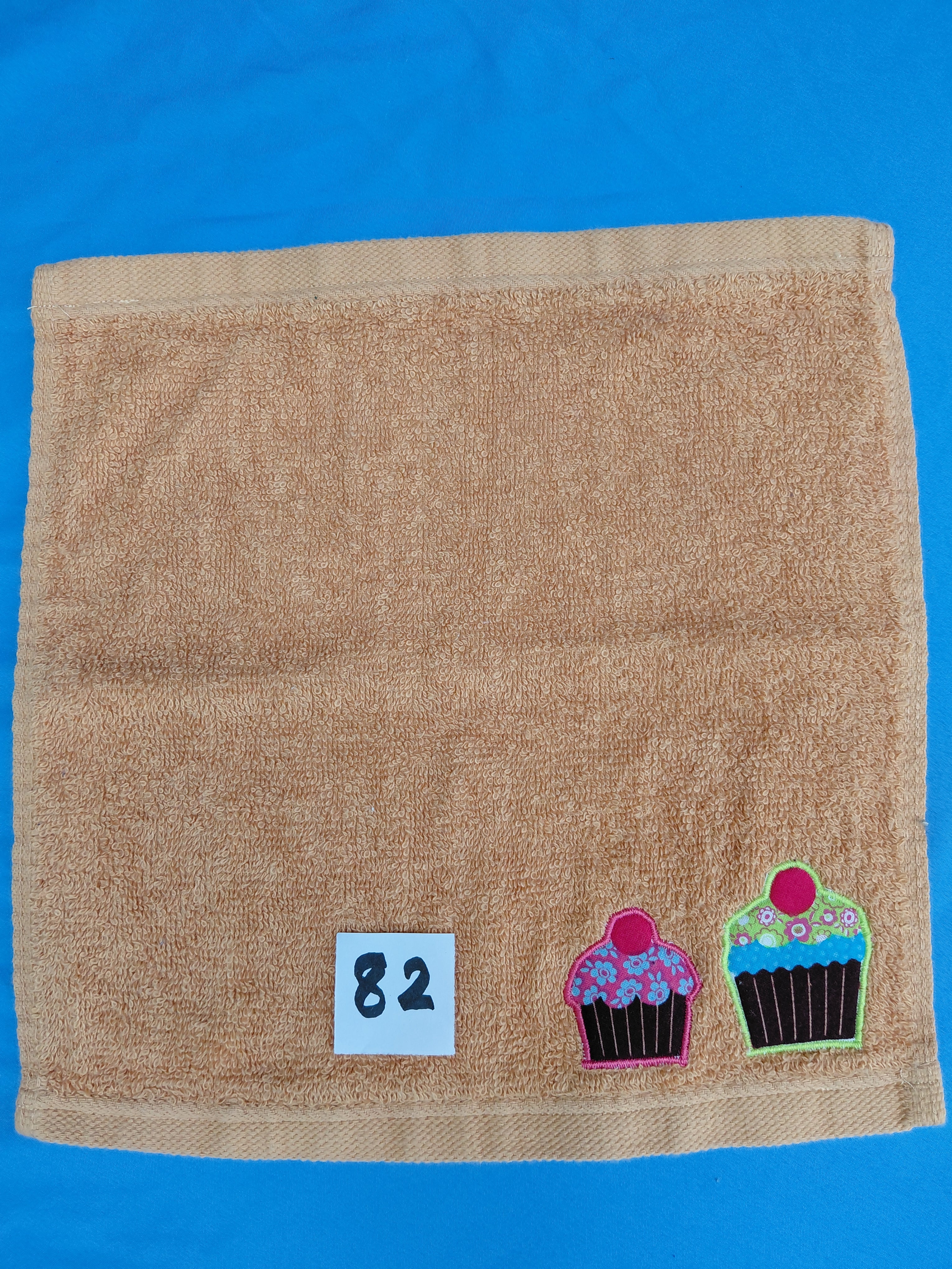 Burnt orange handcrafted embellished washcloth with cupcakes appliqué, reinforced hem