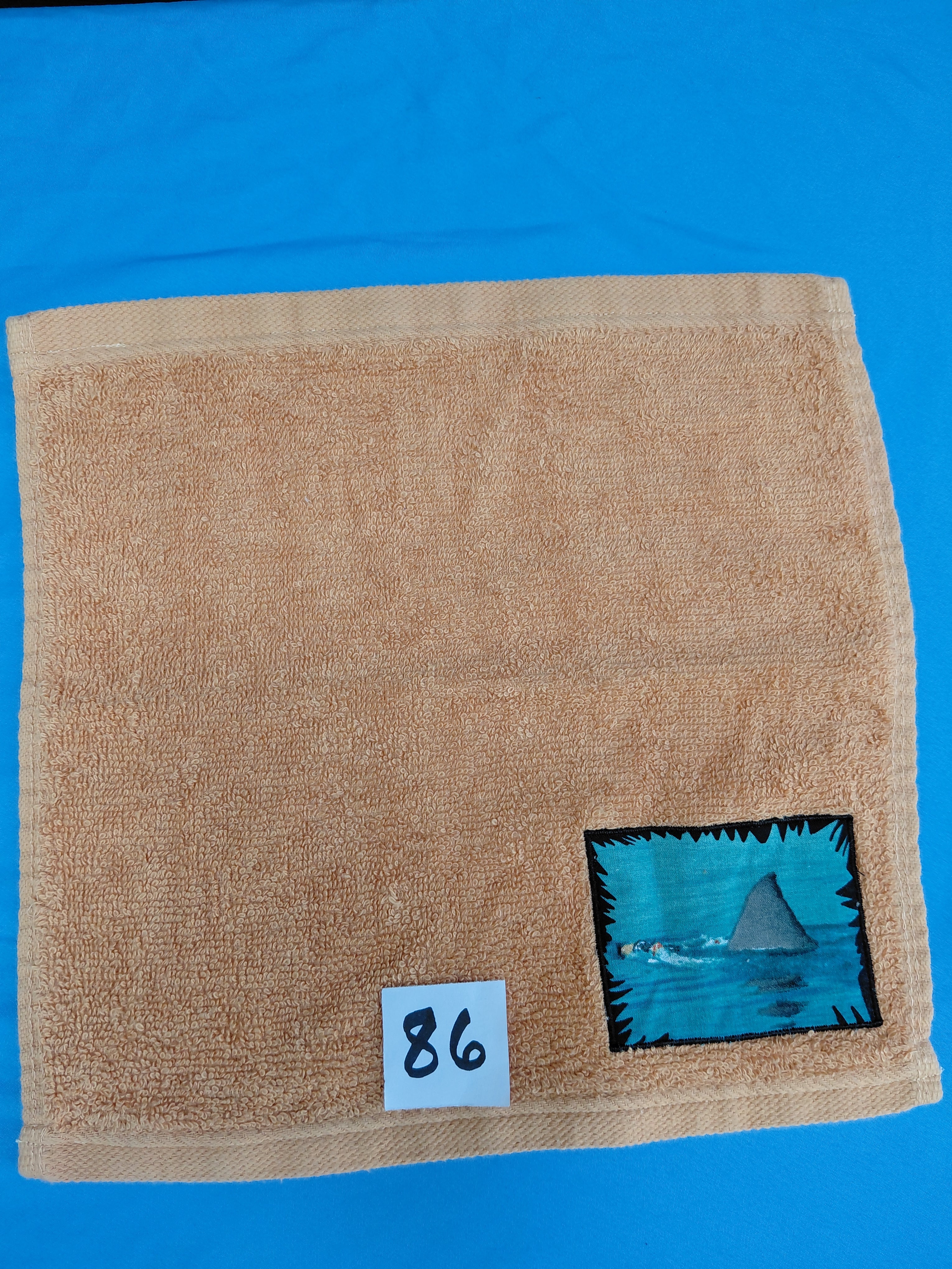 Burnt orange handcrafted embellished washcloth with shark fin appliqué, reinforced hem