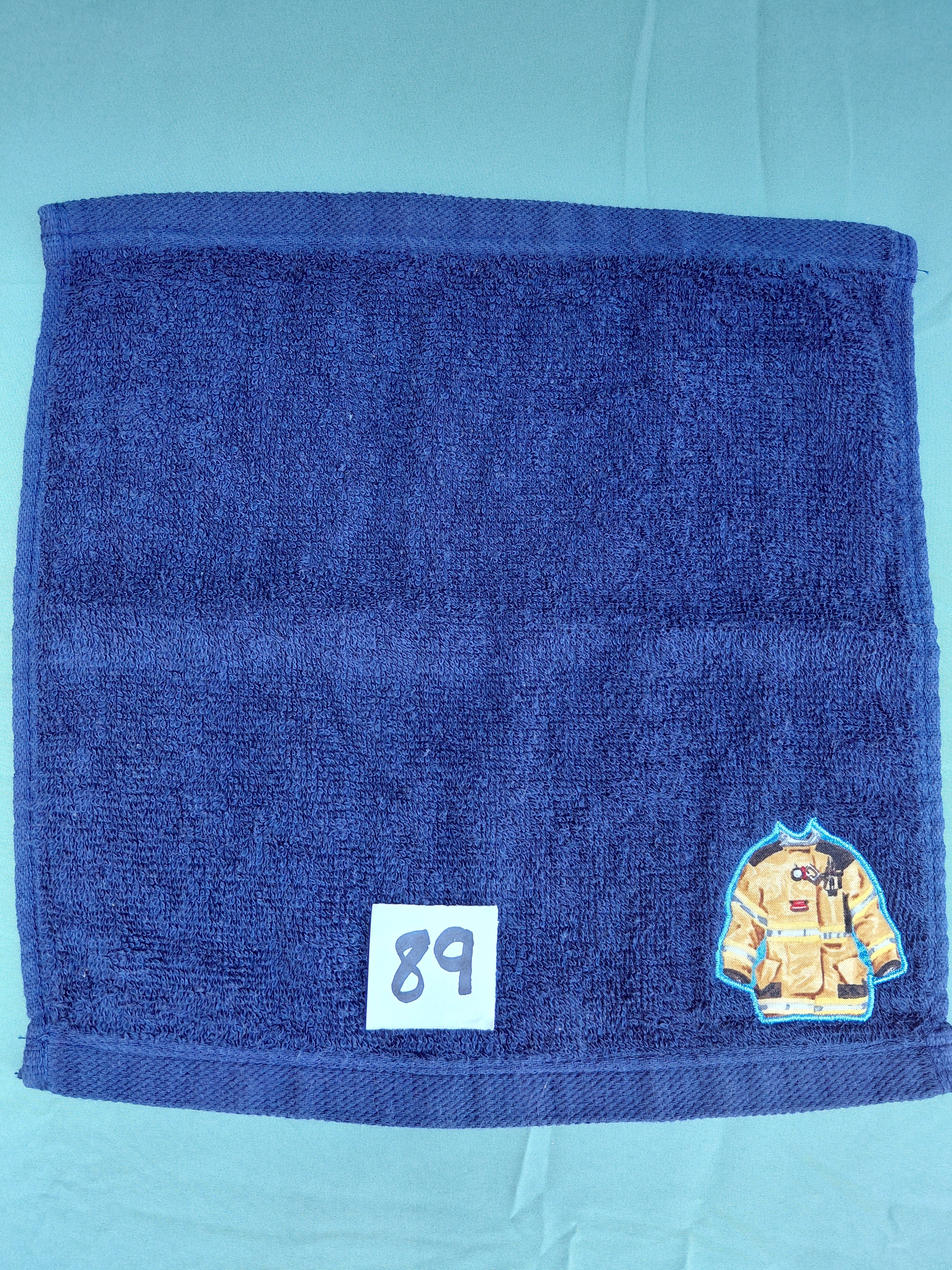Dark blue handcrafted embellished washcloth with firefighter's coat appliqué, reinforced hem