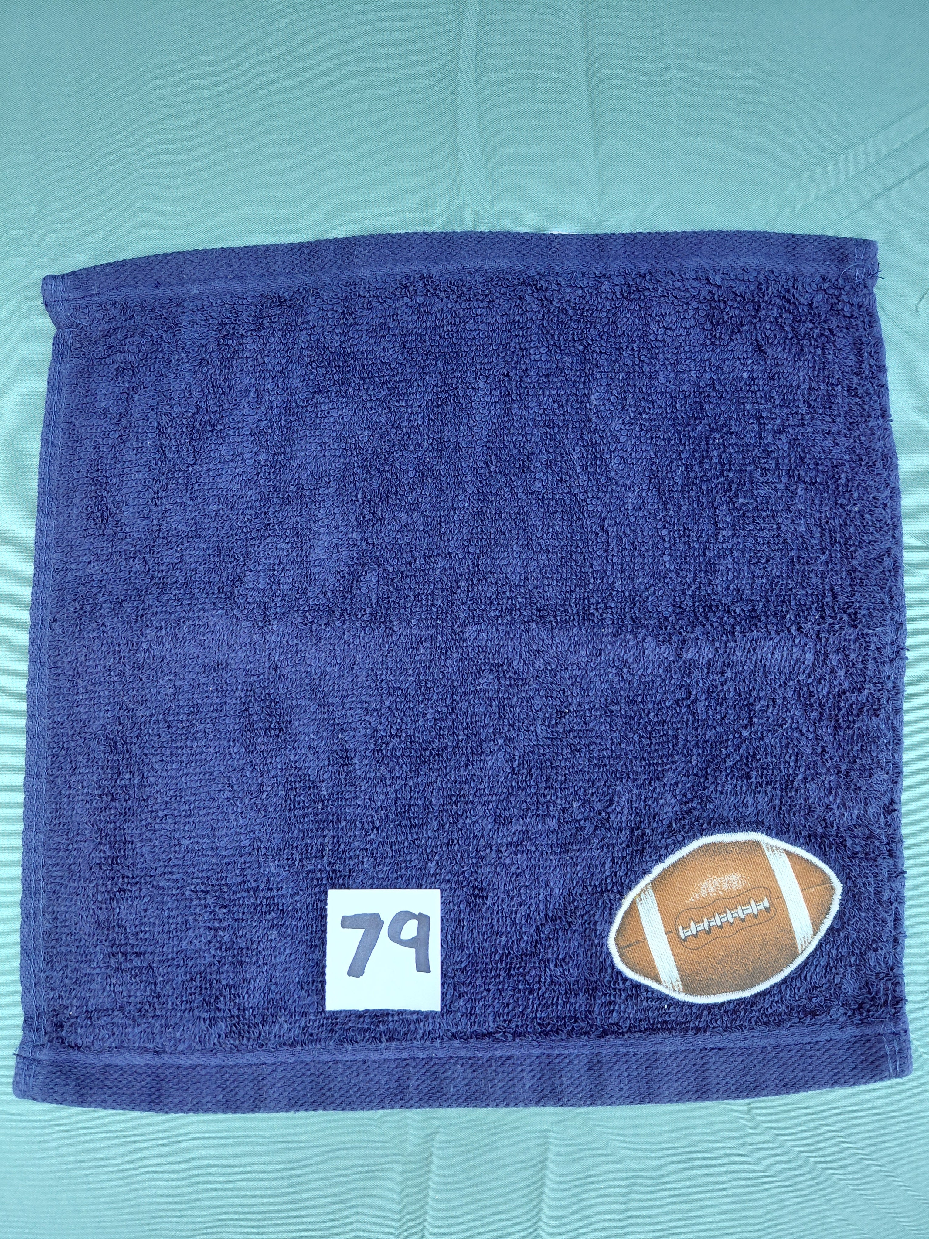 Dark blue handcrafted embellished washcloth with football appliqué, reinforced hem