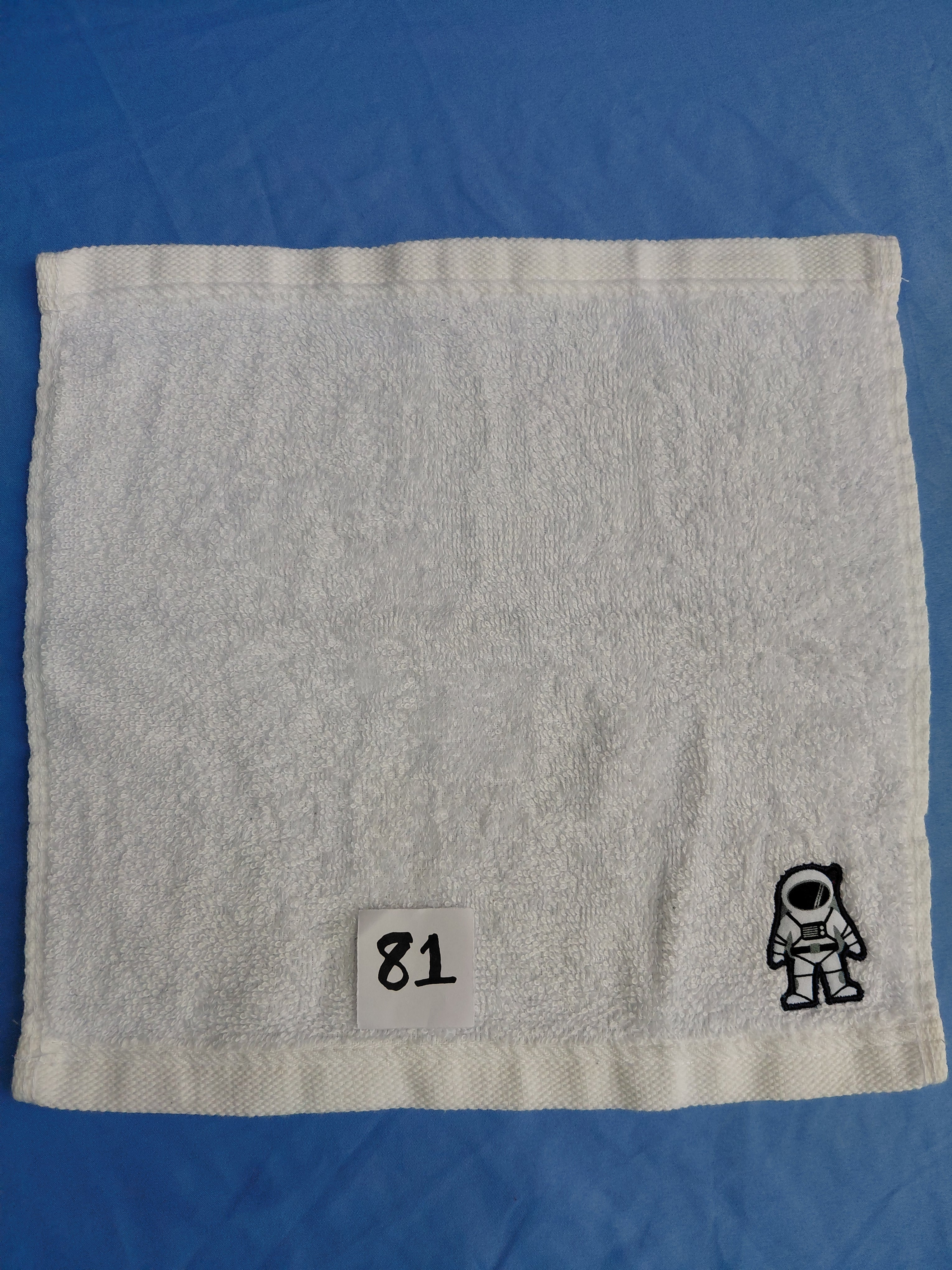 Snow white handcrafted embellished washcloth with astronaut appliqué, reinforced hem