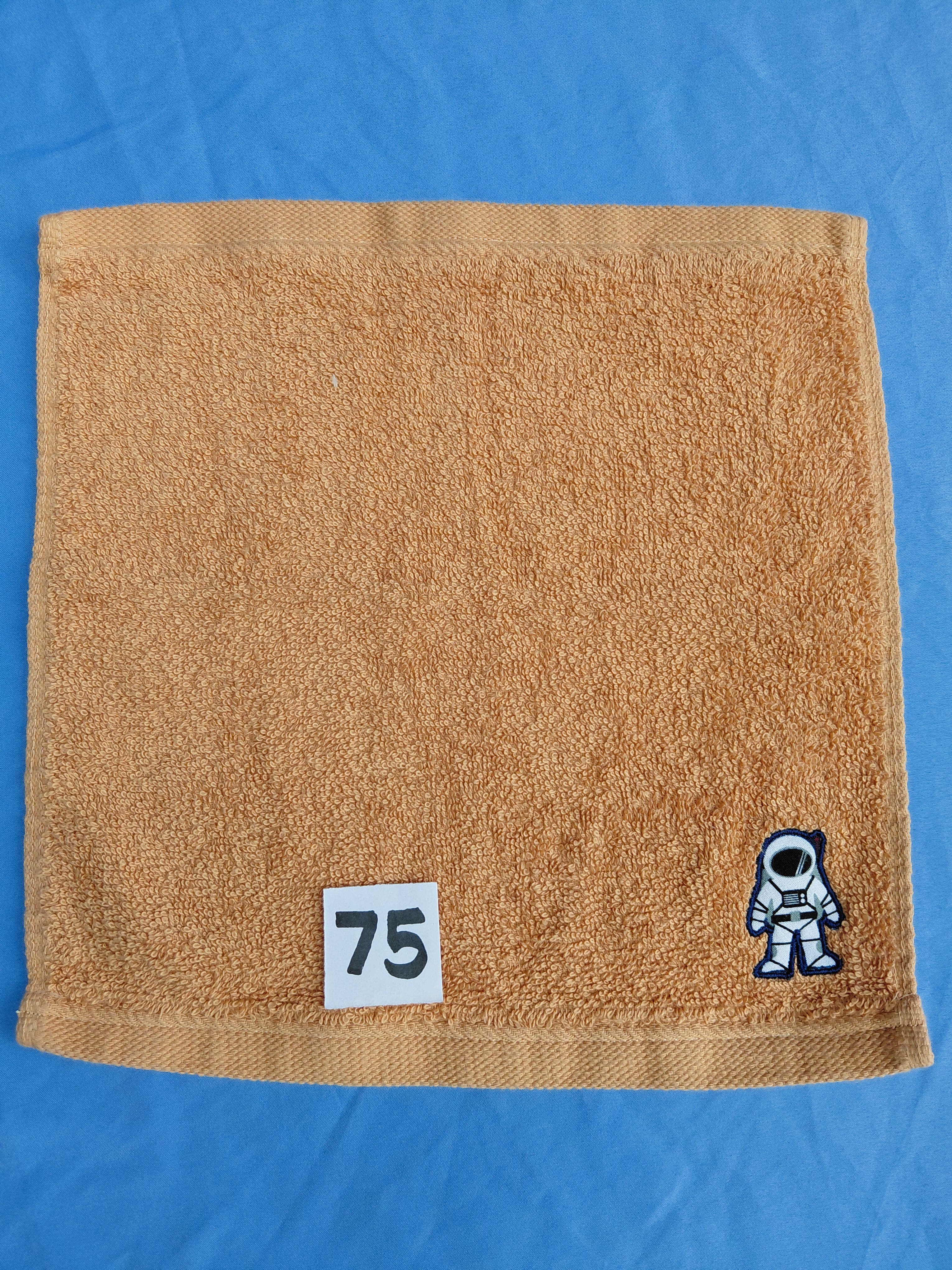 Burnt orange handcrafted embellished washcloth with astronaut appliqué, reinforced hem